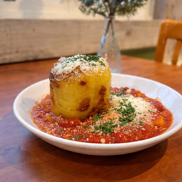 Rigatoni pasta pie with tomato sauce, parmesan cheese, and fresh parsley in a white bowl.
